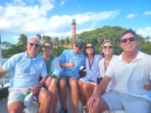A group of people on a Jupter Boat Tour, admiring the scenic lighthouse from our boat.