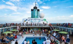 People enjoying a sunny day by the pool on the deck of a margaritaville at sea cruise ship.