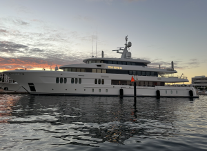 A large white yacht named "TOP FIVE II" is docked at a marina during sunset, with calm water and buildings in the background—perfect for those dreaming of West Palm Beach Boat Tours.
